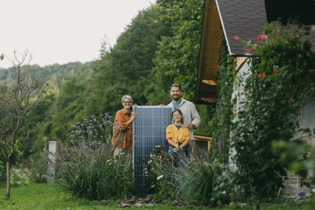 Father mother and daughter standing in garden with solar panel. Solar energy and sustainable